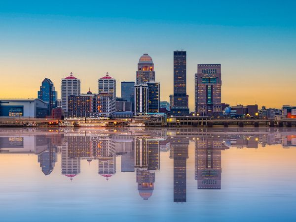 Louisville skyline at sunset reflecting on the river, showcasing the city’s major event venues.