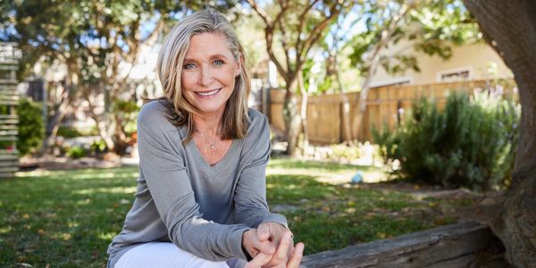 Smiling woman sitting outdoors in a garden.
