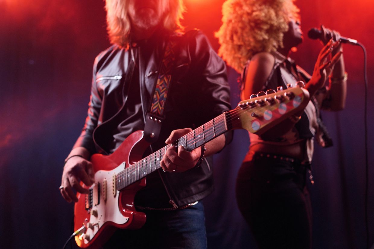 Musicians performing on stage with vibrant lighting and energy.