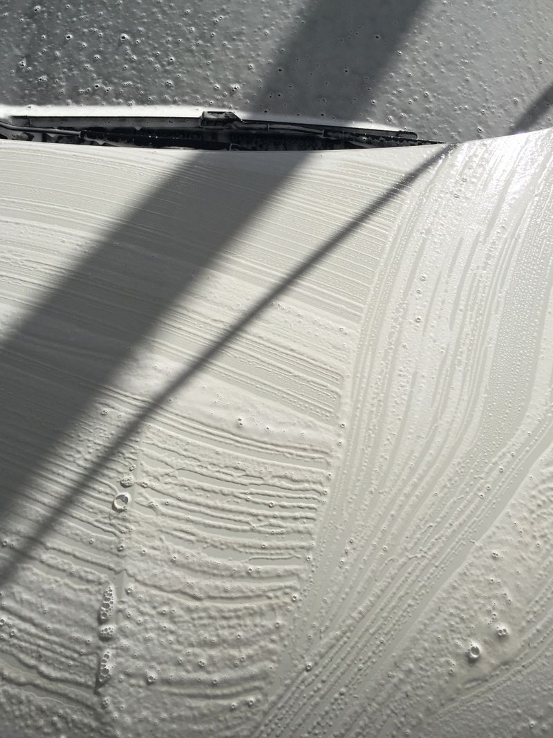High angle view car hood and windshield with soap sud. Car washing