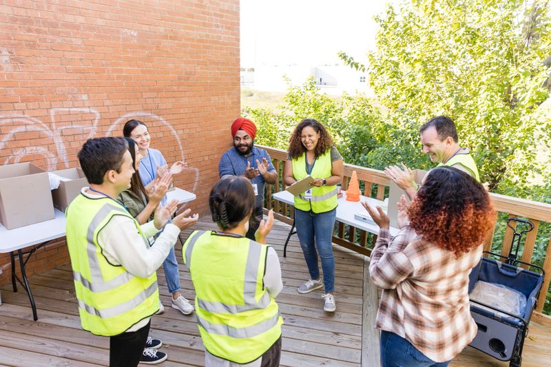 The multiracial group of volunteers stand in a circle to clap and cheer before the event.