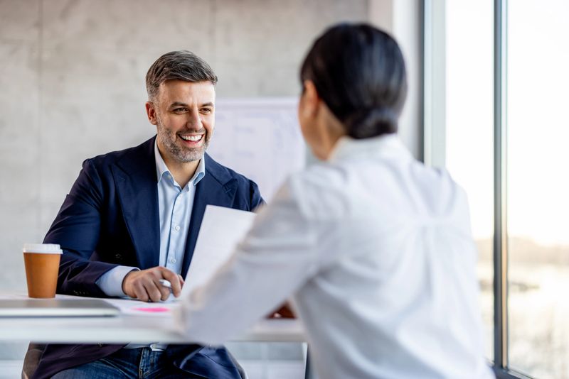 Cheerful businessman having a meeting with a shortlisted job applicant in a modern workplace.