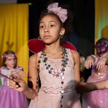 Young girl in a pink fairy costume with wings and star necklace.