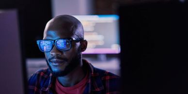 Man coding on computer wearing glasses.