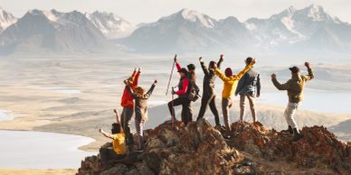 Group of friends celebrating on a mountain peak.