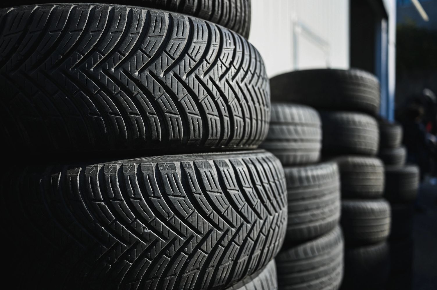 Stacks of black tires with visible tread patterns in an outdoor setting.