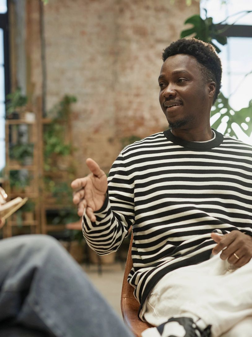 Two men engaged in a thoughtful conversation in a cozy room with natural light.