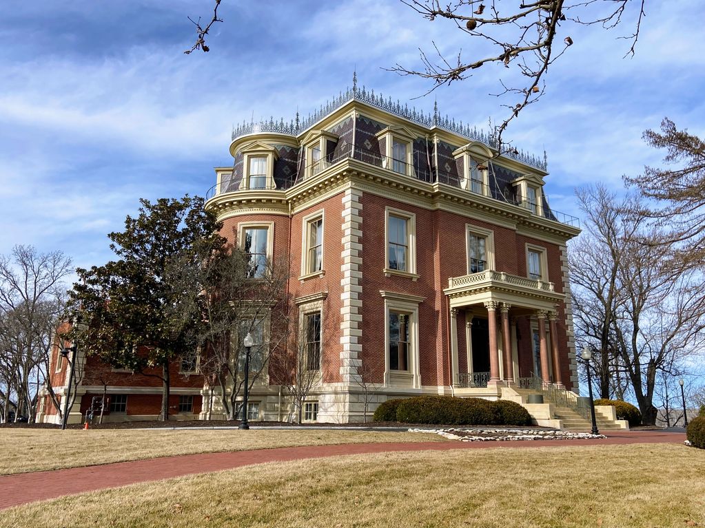Historic brick mansion with intricate roof detailing on a bright day.