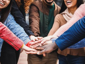 Diverse group stacking hands in unity and support.