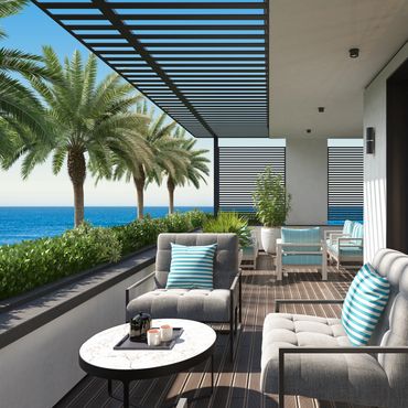 Modern patio with ocean view, comfortable seating, and palm trees.
