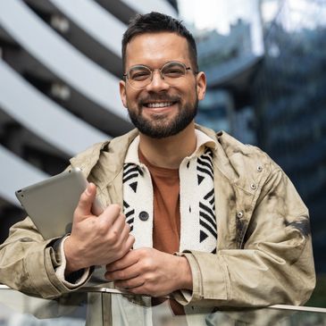 Smiling man holding a tablet outdoors.