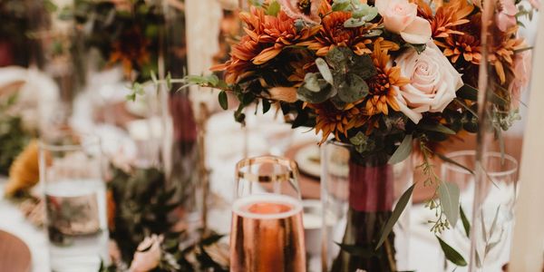 Elegant floral centerpiece with candles and a champagne glass on a beautifully set table.