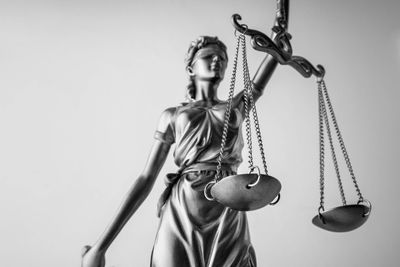 Black and white image of lady justice with the scales of justice. 