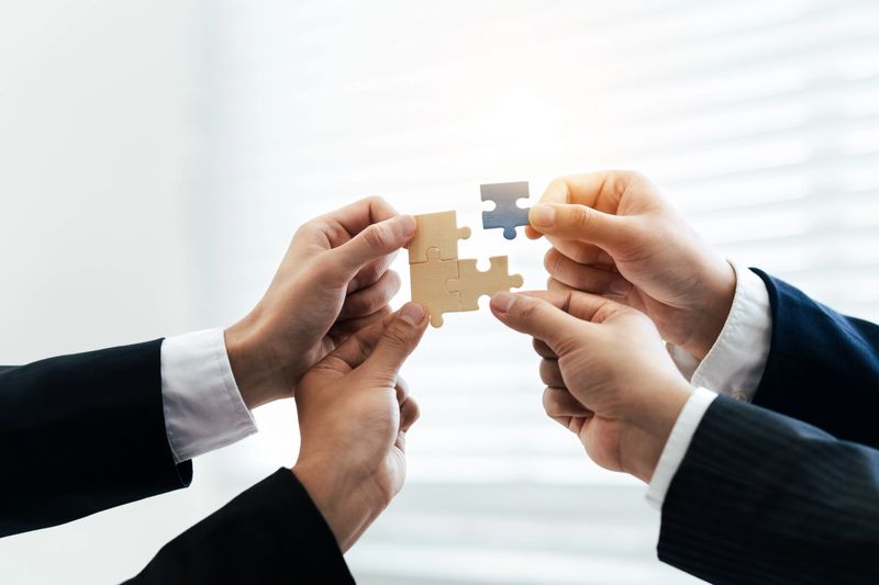 Office workers hold a jigsaw puzzle, teamwork and unity. Charity, volunteering, problem solving, business unity, business teamwork, success and strategy.