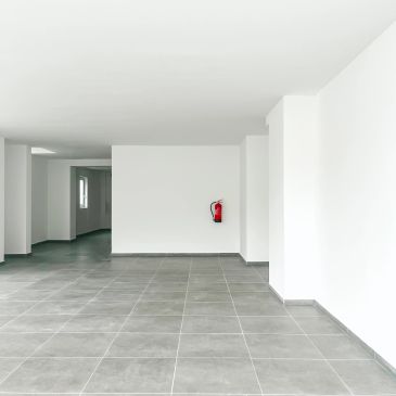 Empty white hallway with gray tiled floor and fire extinguisher.