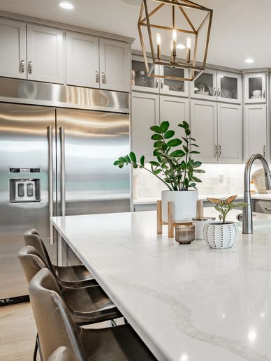 Modern kitchen with marble island and stainless steel fridge.