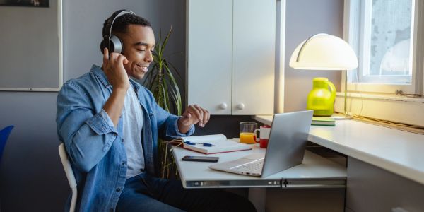 Man wearing headphones working at a desk with a laptop.