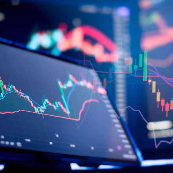 Multiple screens displaying colorful stock market charts and financial data.