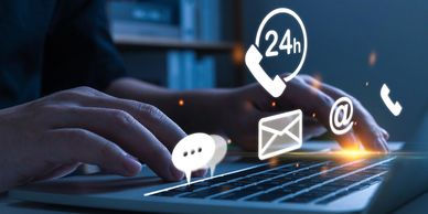 Hands typing on a laptop with digital communication icons floating above.