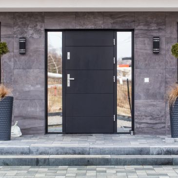 Modern black front door with sidelights and gray stone facade.