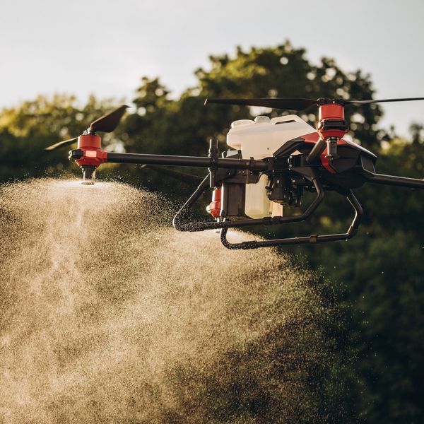 Agricultural drone spraying crops with fine mist over a field.