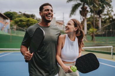 Happy couple playing pickleball outdoors.