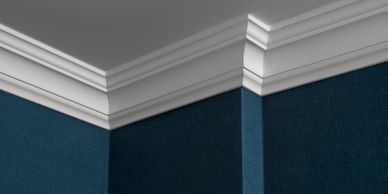 Close-up of white crown molding on blue walls at a ceiling corner.