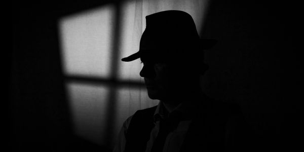 Silhouette of a man in a hat against a window shadow.