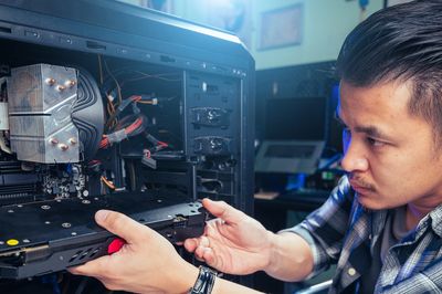 A man installing a graphics card in a desktop computer.