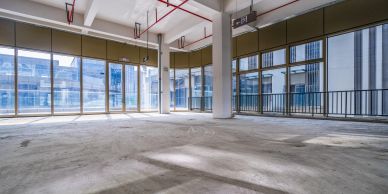 Empty commercial space with large windows and concrete floor.