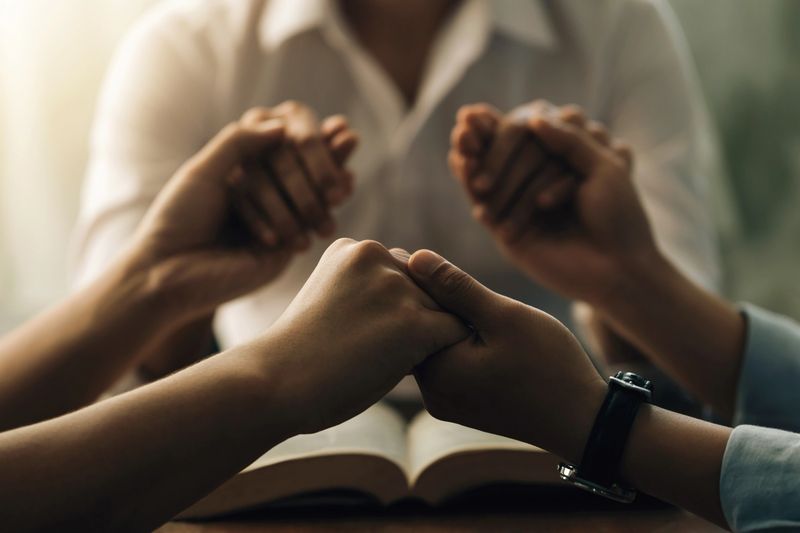 A group of diverse individuals sharing their faith together in a warm, inviting setting.