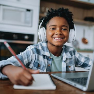 Boy with headphones studying and smiling at home.