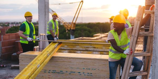Construction workers collaborating on site during sunset.