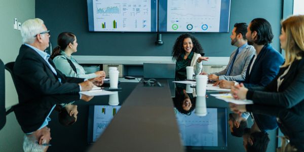 Business team engaged in a meeting with charts on screen.