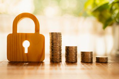 Wooden lock and stacked coins representing financial security and savings.
