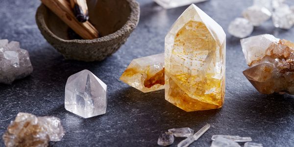 A bowl with palo santo for cleansing the citrine and clear quartz crystals around the bowl.
