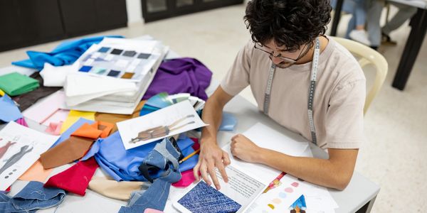 Person working on fashion design with fabric samples.