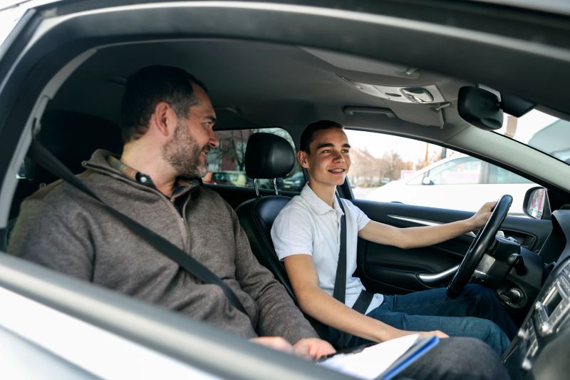 Male teenager learning how to drive a car. About 18 years old, Caucasian male and a male driving instructor.