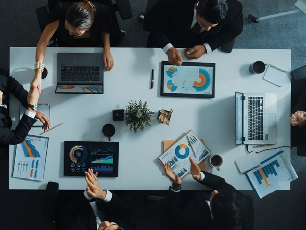 Business team meeting with laptops and charts on a white table.