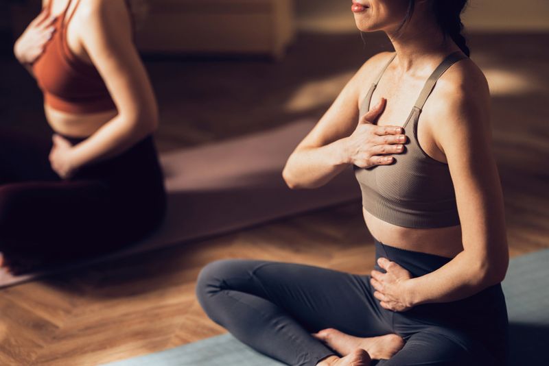 Two women engaging in a yoga session, focused on mindfulness and physical fitness within a tranquil studio setting.