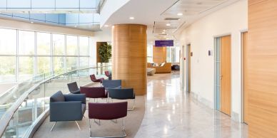 Modern hospital waiting area with chairs and large windows.