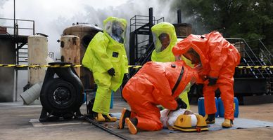 People in hazmat suits perform emergency training with a dummy.