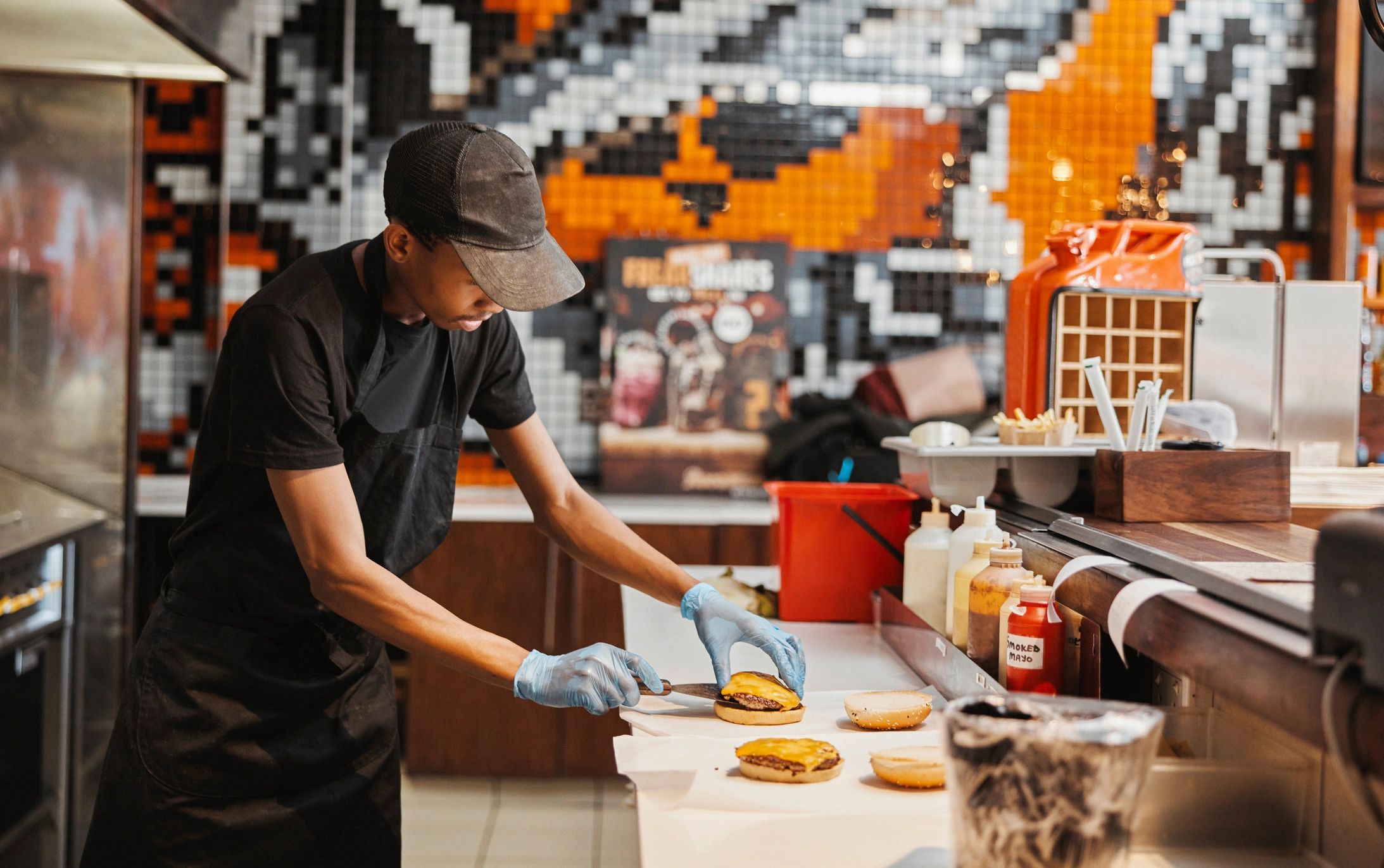 Person preparing cheeseburgers in a kitchen.