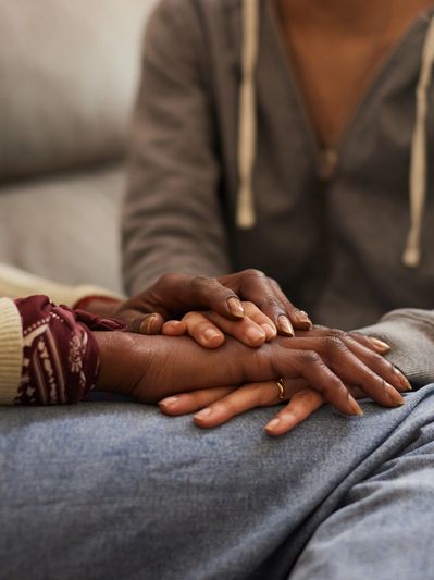 Close up of two adults holding hands in support.