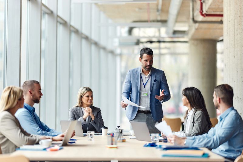 Mid adult male CEO communicating with group of his colleagues during a meeting in the office.