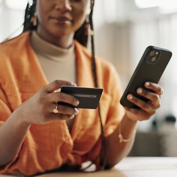 Person holding a credit card and smartphone for online payment.