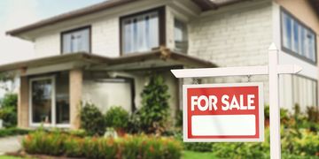Modern house with a "For Sale" sign in the front yard.