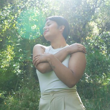 A person enjoys a peaceful moment outdoors with sunlight and greenery.