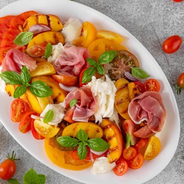 Colorful grilled peach salad with prosciutto and basil.