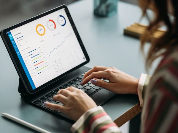 Person working on a tablet with data analytics dashboard visible.